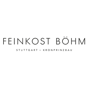 Ein dunkelgrauer „Feinkost Böhm“ Schriftzug in geraden Großbuchstaben. Darunter steht ebenfalls in Großbuchstaben der gleichen Farbe aber in kleinerer Schrift „Stuttgart – Kronprinzbau“.